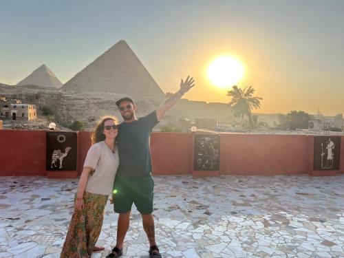 een man en een vrouw die voor de piramiden staan bij El Khalil Pyramids Inn in Caïro