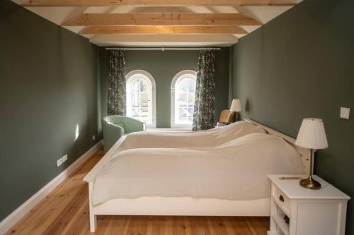 a bedroom with a large white bed and green walls at A Refuge Built for a King in Halbe