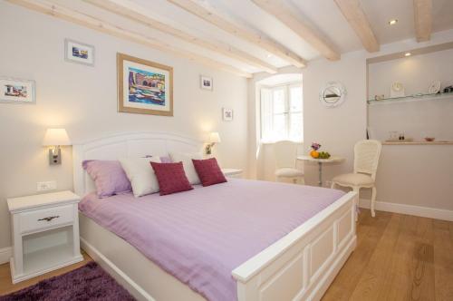 a bedroom with a large white bed with purple sheets at Studio Apartments Sonatina in Dubrovnik