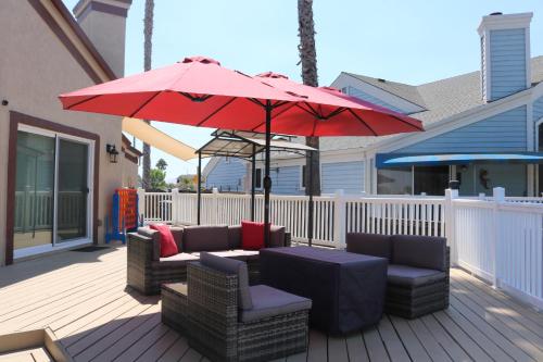 a patio with two couches and a red umbrella at Lakefront Gem: Private Dock in Discovery Bay