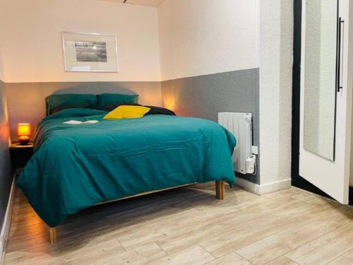 une chambre avec un lit avec une couette verte dans l'établissement Le Fauriel - Parking gratuit - Centre ville, à Saint-Étienne