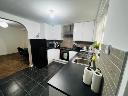a kitchen with a sink and a black refrigerator at Liberty Inn Room with sharing toilet and kitchen in Liverpool