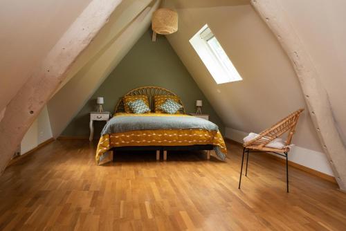 een slaapkamer op zolder met een bed en een stoel bij L'Aube Normande 