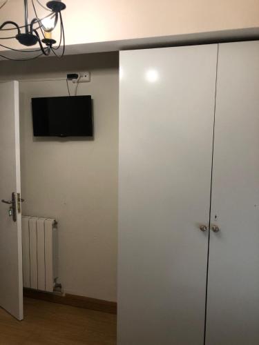 um armário branco com uma televisão na parede em Habitación Doble em Estella