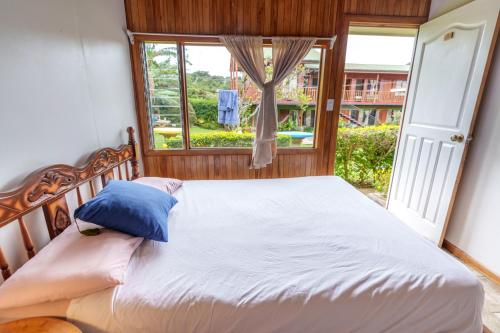 a bed with a blue pillow in a room with a window at Pension Santa Elena in Monteverde Costa Rica