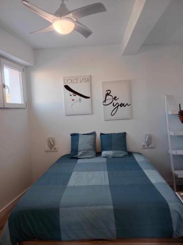 um quarto com uma cama azul e uma ventoinha de tecto em Ático en el centro de Estella em Estella