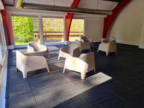a waiting room with white chairs and windows at Chalet Het Bosnestje Durbuy in Durbuy