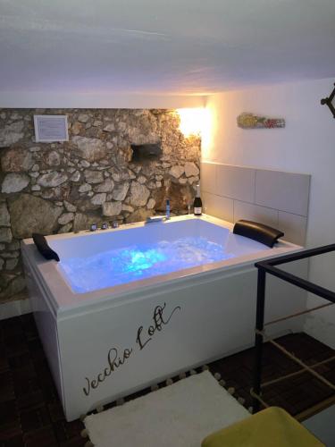 a bath tub in a room with a stone wall at Vecchio Loft con Jacuzzi in Siracusa