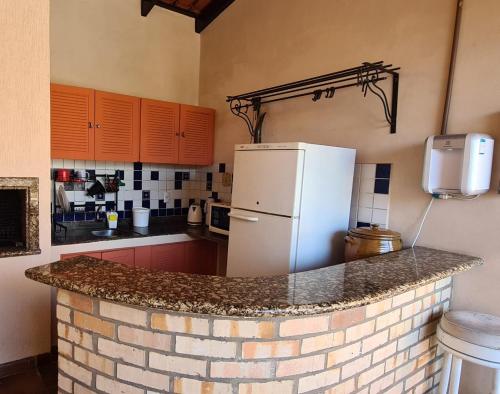 a kitchen with a brick counter with a refrigerator at Suíte Theo in Blumenau