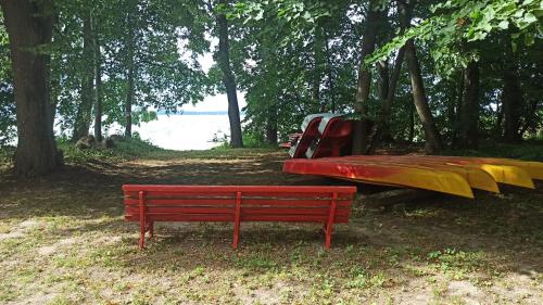 a red park bench next to a yellow slide at Dom Królewski Róg in Giżycko