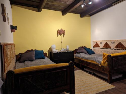 1 dormitorio con 2 camas y pared amarilla en Lóci Palócház, en Nagylóc