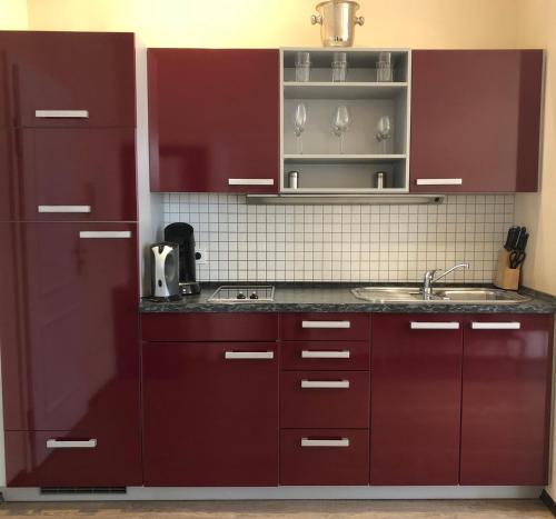 eine Küche mit roten Schränken und einem Waschbecken in der Unterkunft Deluxe Suite mit Wintergarten in Frankfurt am Main