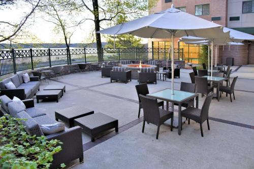 a patio with tables and chairs and an umbrella at Courtyard by Marriott Boston Waltham in Waltham
