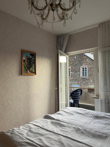 Schlafzimmer mit einem Bett, einem Fenster und einem Kronleuchter in der Unterkunft Landhotel-Restaurant Wolfshof in Traben-Trarbach