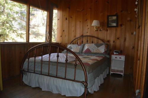ein Schlafzimmer mit einem Bett in einer Blockhütte in der Unterkunft Charming 1927 Lake Front Home - Hargrave in Bass Lake