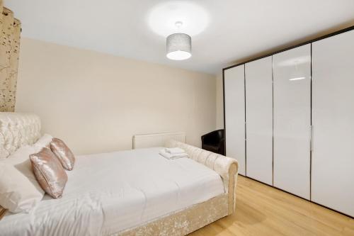 a white bedroom with a bed and a cabinet at The Smeaton Apartment, Central City Centre in Plymouth