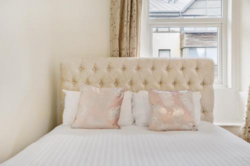 een bed met roze kussens en een groot raam bij The Smeaton Apartment, Central City Centre in Plymouth