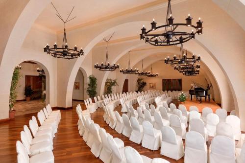 a large hall with white chairs and a piano at Kempinski Hotel San Lawrenz in San Lawrenz