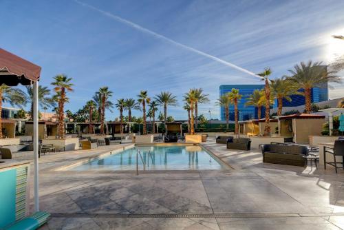a pool with chaise lounge chairs and palm trees at LUXE 702 MGM Signature with Balcony in Las Vegas