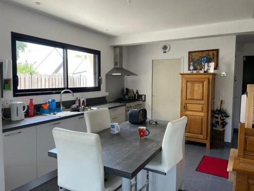 - une cuisine avec une table en bois et des chaises blanches dans l'établissement Maison étape, à Muzillac