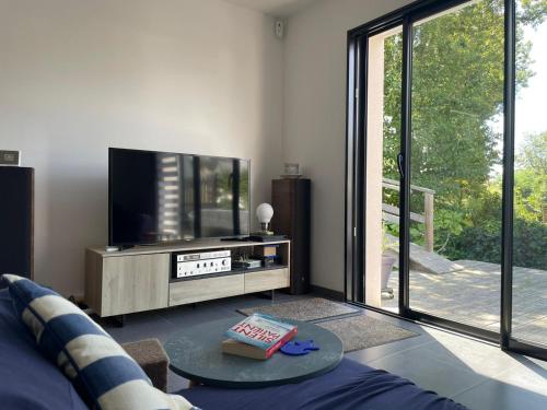 un salon avec une télévision à écran plat et une table dans l'établissement Maison étape, à Muzillac