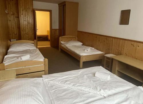 a room with three beds and a desk and a room with two beds at Chata VISTA Strážné in Strážné