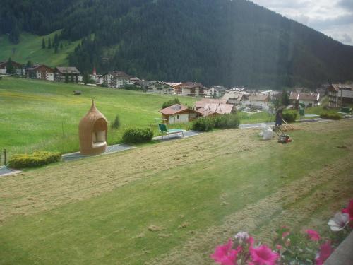 a person is standing in a field with a village at Garni La Majon in Selva di Val Gardena