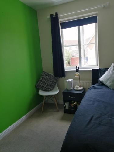 ハルステッドにある59 Halstead - Gorgeous single bedroom with private bathroomの緑の壁のベッドルーム1室、ベッドの横に椅子1脚が備わります。