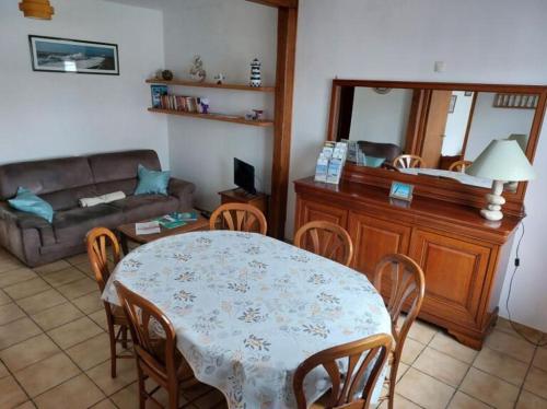 een woonkamer met een tafel en stoelen en een bank bij Le Saint Ju' in Friville-Escarbotin