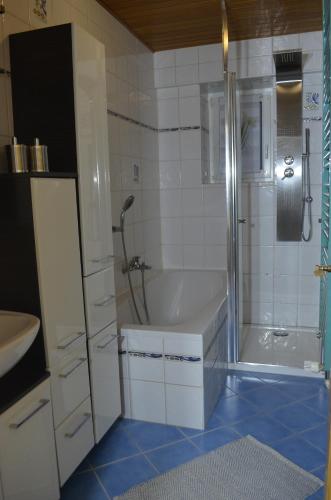 a bathroom with a tub and a shower and a sink at Gemütliche Ferienwohnung in Kirchenpingarten