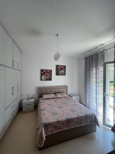 ein weißes Schlafzimmer mit einem Bett und einem Fenster in der Unterkunft Anushe's apartament in Pogradec