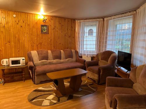 a living room with a couch and chairs and a tv at Садиба "Джерело" in Yaremche