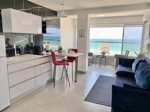 a kitchen and living room with a view of the ocean at Seaside cozy apartment in Haifa
