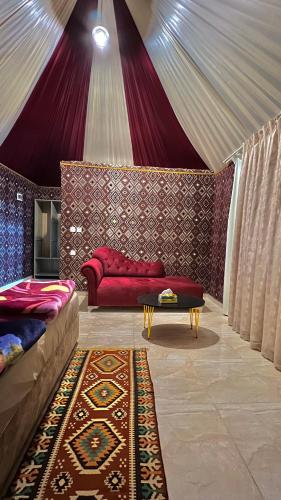 a living room with a red couch and a rug at RUM STARDUST lUXURY CAMP in Wadi Rum