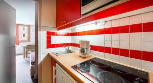 a kitchen with red and white tiles on the wall at Les Silènes & Soldanelle in Plagne 1800
