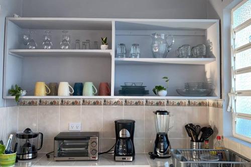 a kitchen with a counter top with dishes on shelves at Casa Colibrí in Cozumel