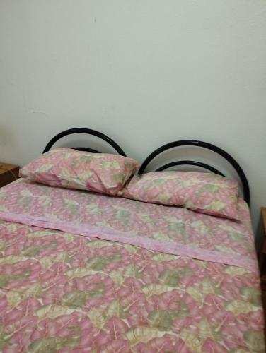 a bed with a pink comforter and two pillows at casa vacanze Cettina home 2 mt 50 dal mare in Terra Mala