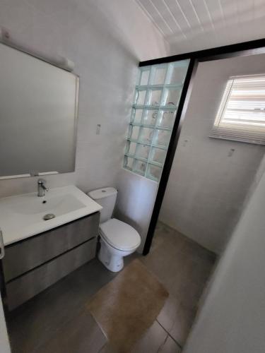 a bathroom with a toilet and a sink and a window at LocaGuyane in Matoury