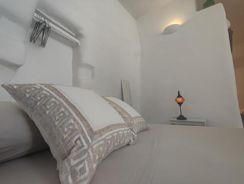 a white bed with a pillow and a window at Καμάρα (Kamara) cave rooms in Triovasálos