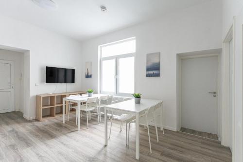 Habitación blanca con mesas, sillas y TV. en T&K Apartments - 1 to 4 Room Apartments - 20min to TradeFair Messe Airport Düsseldorf, en Duisburg