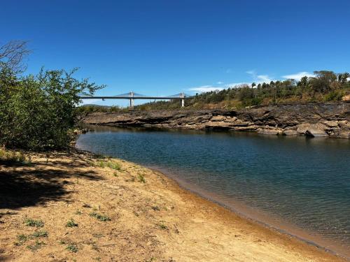 a body of water with a bridge in the background at Pousada Sossego do Tocantins in Lajeado