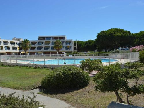 une grande piscine avec un bâtiment en arrière-plan dans l'établissement Studio climatisé 4 pers avec piscine et parking à Port Camargue - FR-1-250-230, au Grau-du-Roi