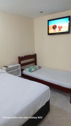 Cette chambre comprend 2 lits et une télévision murale. dans l'établissement Casa temporada paraíso, à Cabo Frio