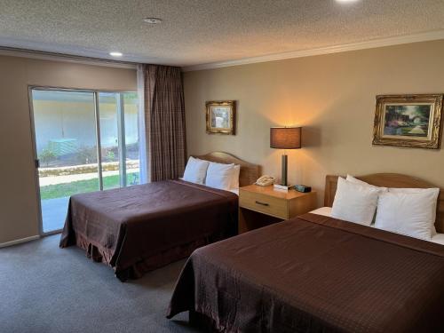 um quarto de hotel com duas camas e uma janela em Lamp Liter Inn em Visalia