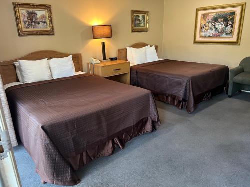a hotel room with two beds and a chair at Lamp Liter Inn in Visalia