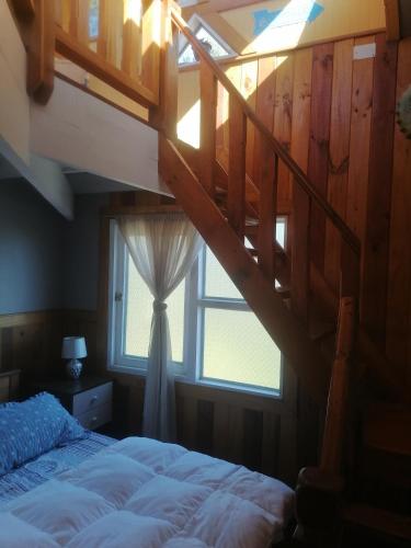 1 dormitorio con escalera, cama y ventana en Habitación tipo Loft de la Estancia en El Quisco