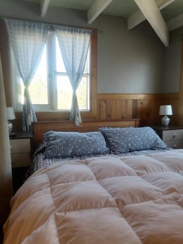 a large bed in a bedroom with two windows at Habitación tipo Loft de la Estancia in El Quisco