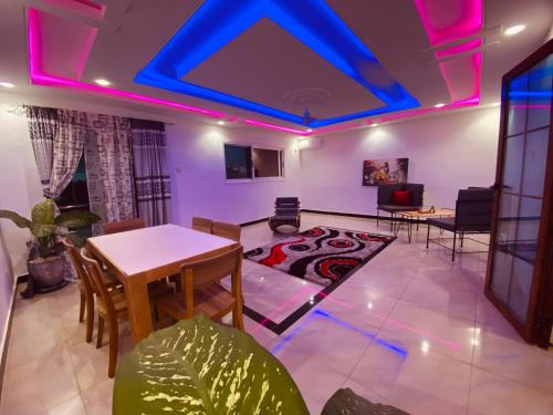 een woonkamer met een tafel en stoelen en paarse verlichting bij Ngor Rooftop Terrace & Apartment in Dakar