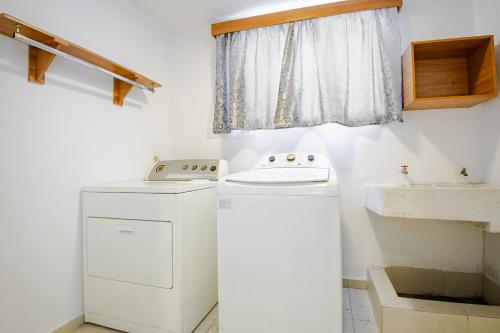 een badkamer met een wasmachine en een wastafel bij Estrena casa a minutos del aeropuerto in Monterrey