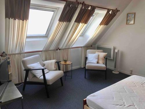 a hotel room with two chairs and a bed and a tv at Appartement aux Minimes Magnifique Vue Mer au pied de la Plage 50m2-2ch. in La Rochelle